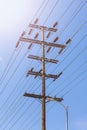 Old wooden high voltage post against sun and blue sky. Royalty Free Stock Photo