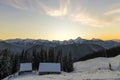 Old wooden house, hut and barn in deep snow on mountain valley, spruce forest, woody hills on clear blue sky at sunrise copy space Royalty Free Stock Photo