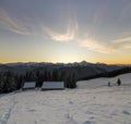 Old wooden house, hut and barn in deep snow on mountain valley, spruce forest, woody hills on clear blue sky at sunrise copy space Royalty Free Stock Photo