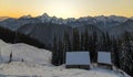 Old wooden house, hut and barn in deep snow on mountain valley, spruce forest, woody hills on clear blue sky at sunrise copy space Royalty Free Stock Photo