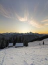 Old wooden house, hut and barn in deep snow on mountain valley, spruce forest, woody hills on clear blue sky at sunrise copy space Royalty Free Stock Photo