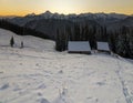 Old wooden house, hut and barn in deep snow on mountain valley, spruce forest, woody hills on clear blue sky at sunrise copy space Royalty Free Stock Photo