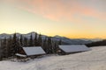 Old wooden house, hut and barn, pile of firewood in deep snow on mountain valley, spruce forest, woody hills on clear blue Royalty Free Stock Photo