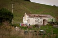 Old wooden house with peeling white paint near a roadside in rural Tolaga Bay, East Coast, North Island Royalty Free Stock Photo