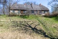 an old wooden house on the top of a hill and an old tree with a shadow in the grass on the background of a blue sky Royalty Free Stock Photo