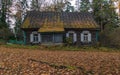 An old wooden house with white window shutters in the fall Royalty Free Stock Photo