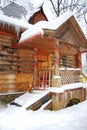 An old wooden house in winter. The wooden house made of timber is covered with snow and ice. Icicles hang from the roof