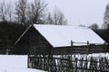 An old wooden hut. Abandoned Russian village covered in snow. Log house with a barn with a wooden wicker fence. Royalty Free Stock Photo