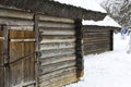 An old wooden hut. Abandoned Russian village covered in snow. Log house with a barn with a wooden wicker fence. Royalty Free Stock Photo