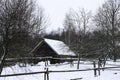 An old wooden hut. Abandoned Russian village covered in snow. Log house with a barn with a wooden wicker fence. Royalty Free Stock Photo