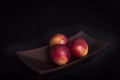 Old wooden Japanese tray with three peaches on black background Royalty Free Stock Photo