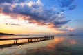 Old wooden jetty, pier reveals views of the beautiful lake, blue sky with cloud. Sunrise enlightens the horizon with orange warm Royalty Free Stock Photo