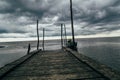 Old wooden jetty, pier, during storm on the sea.  sea horizon under huge dark storm sky and clouds Royalty Free Stock Photo