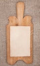 Old wooden kitchen board with aged paper on the burlap Royalty Free Stock Photo