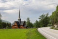 Old wooden Kvikne Kirke in Innlandet, Norway with green fields and a winding road
