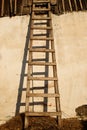 Old wooden ladder with shadow near whitewashed plastered wall of the aged house Royalty Free Stock Photo