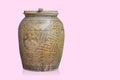 Old wooden lid on brown and yellow ceramic jar on pink background, object, decor, vintage, copy space Royalty Free Stock Photo