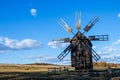 Old wooden mill for grinding grain into flour, against the background of a field and a clear, blue sky with a small amount of Royalty Free Stock Photo