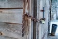 Old wooden outdoor bathroom secured with rusty chain and long shackle padlock Royalty Free Stock Photo