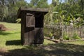 Old wooden outhouse by garden with forest in the background Royalty Free Stock Photo