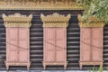 Old wooden painted windows. Carved yellow architraves, closed coral shutters. Ulan-Ude,Russia. Royalty Free Stock Photo