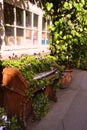 Old wooden piano on the street under the window covered with ivy and flowers Royalty Free Stock Photo