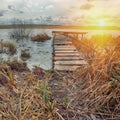 Old wooden pier with dry reed on sunset Royalty Free Stock Photo