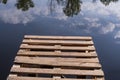 Old wooden pier above a calm reflective river, surrounded by bright spring greenery and peaceful nature. Royalty Free Stock Photo