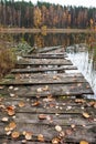 Old wooden pier with fall yellow leaves on a forest lake. Quiet and calm. Place for relaxation and meditation. Autumn time Royalty Free Stock Photo