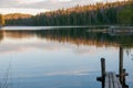 The old wooden pier on a lake in spring forest. Trees and sky reflected in the calm waters of a forest lake.  Natural background. Royalty Free Stock Photo