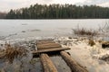 Old wooden pier on small country lake. Melted ice near the shore on the lake in the woods. Evening time in spring Royalty Free Stock Photo