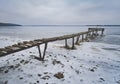 An old wooden pier in winter on a frozen lake goes into the distance Royalty Free Stock Photo