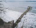 An old wooden pier in winter on a frozen lake goes into the distance Royalty Free Stock Photo