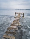 An old wooden pier in winter on a frozen lake goes into the distance Royalty Free Stock Photo