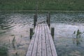 old wooden plank boardwalk trail in swamp area near water - vintage retro look