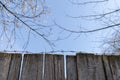 Old wooden plank, fence with barbed wire, against the blue sky