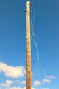 Old wooden pole with broken electric wires. Close-up view of old abandoned wooden pole for fixing electrical wires.