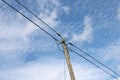 Old wooden power pole with power lines against blue cloudy sky Royalty Free Stock Photo