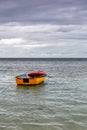 Old wooden red and orange fishing boat anchored at Baie Lazare Public Beach on Mahe Island, Seychelles, overcast cloudy sky Royalty Free Stock Photo