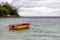 Old wooden red and orange fishing boat anchored at Baie Lazare Public Beach on Mahe Island, Seychelles. Royalty Free Stock Photo