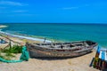 Old wooden row-boat, used for fishing, with nets on a sandy beach, blue sky and wavy sea water on a sunny summer day Royalty Free Stock Photo