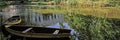 2 old wooden rowboats lying on water on the shore of a quiet idyllic lake. Trees of green summer forest reflect on smooth surface Royalty Free Stock Photo