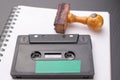 Old wooden rubber stamp and audio cassette on a white piece of notebook. Secret recordings of political talks Royalty Free Stock Photo
