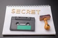 Old wooden rubber stamp and audio cassette on a white piece of notebook. Secret recordings of political talks Royalty Free Stock Photo