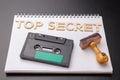 Old wooden rubber stamp and audio cassette on a white piece of notebook. Secret recordings of political talks Royalty Free Stock Photo