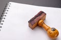 Old wooden rubber stamp on a white piece of notebook. Office accessories on a table Royalty Free Stock Photo