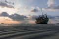 The old wooden ruined fishing boat set aground on the beach at Sunset time Royalty Free Stock Photo