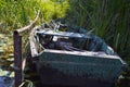 Old wooden shabby dilapidated broken boat for swimming on the banks of the river, lake, sea in the grass and reeds in nature Royalty Free Stock Photo