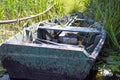 Old wooden shabby dilapidated broken boat for swimming on the banks of the river, lake, sea in the grass and reeds in nature Royalty Free Stock Photo