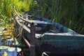 Old wooden shabby dilapidated broken boat for swimming on the banks of the river, lake, sea in the grass and reeds in nature Royalty Free Stock Photo